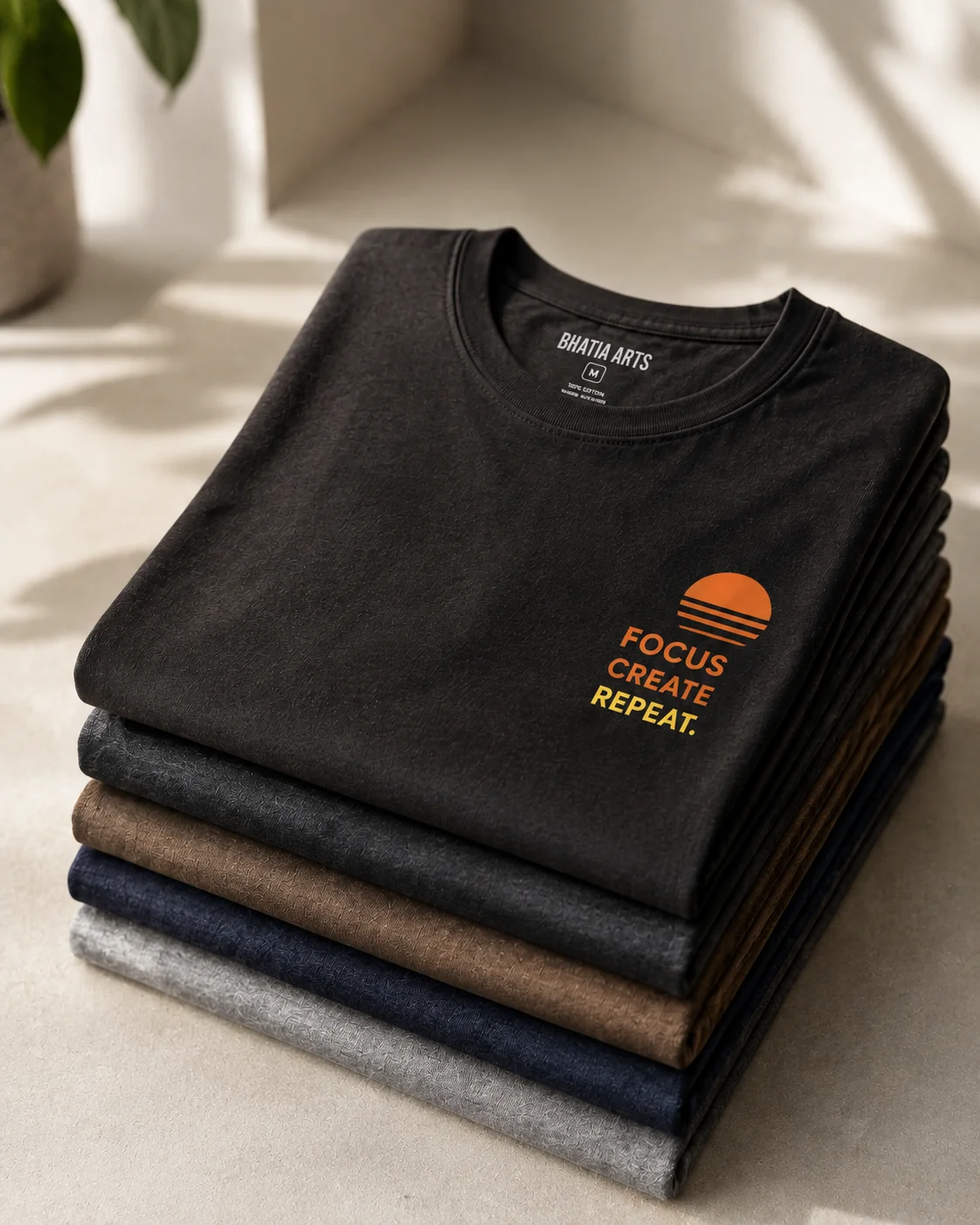Folded stack of printed Bhatia Arts t-shirts